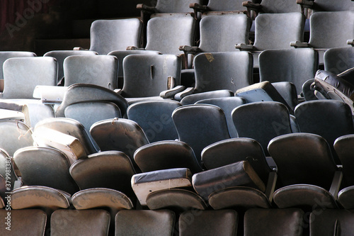 Pile of old worn seats awaiting renovation in historic vintage movie theater building.