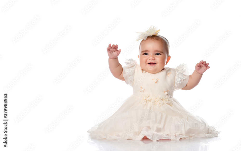 beautiful baby child in a festive dress and a headband, sitting on the floor and joyfully raised her hands. shot on a white background. beautiful baby child in a festive dress and a headband, sitting on the floor and joyfully raised her hands. shot on a white background.