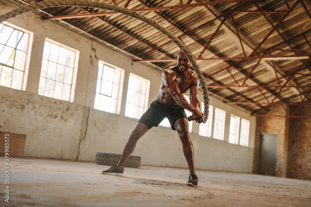 Man exercising with battle rope in abandoned warehouse