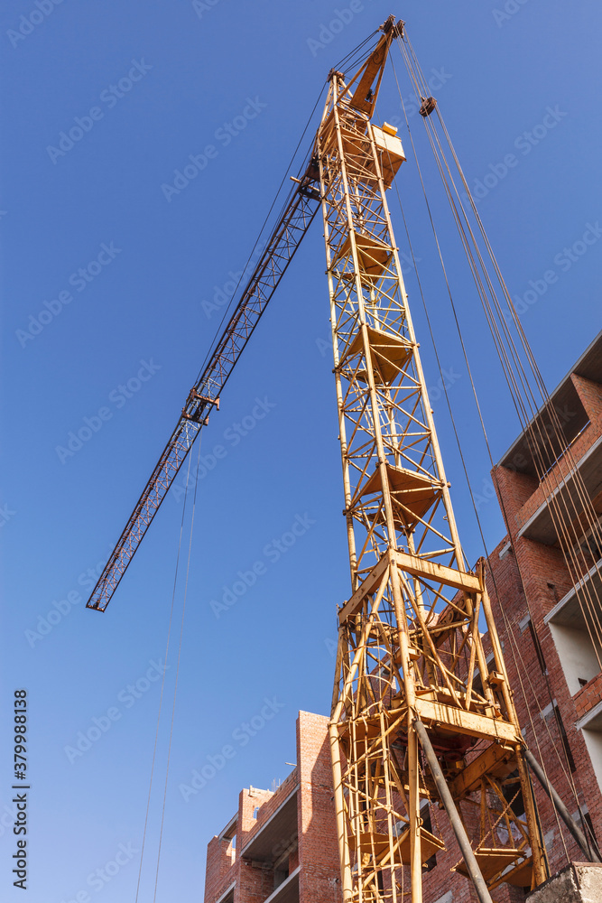 Bottom view of a tall tower crane near a brick building Bottom view of a tall tower crane near a brick building