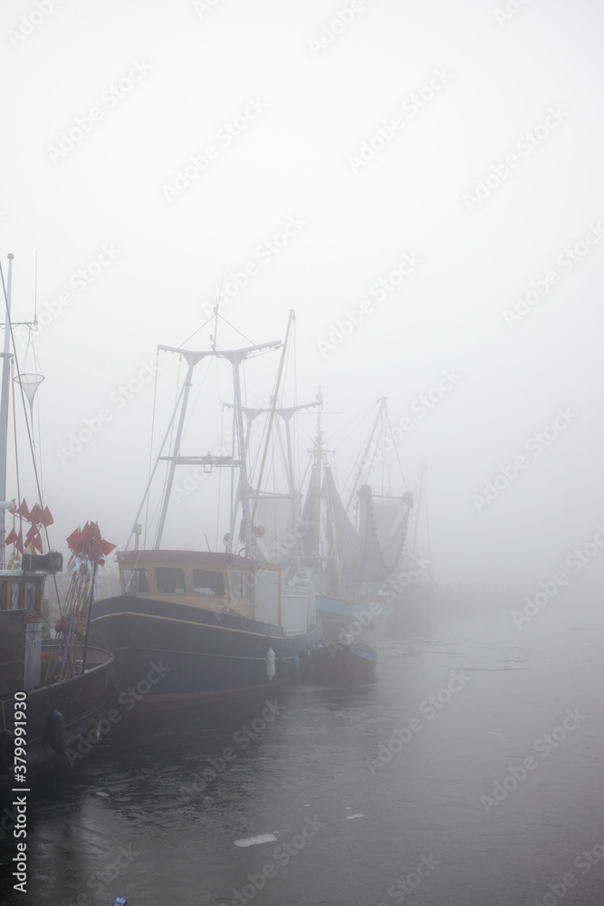 Fishing boats in the harbor on a foggy morning Fishing boats in the harbor on a foggy morning