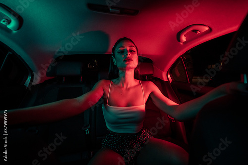 chica joven de moda en un coche con luces de colores moderno

