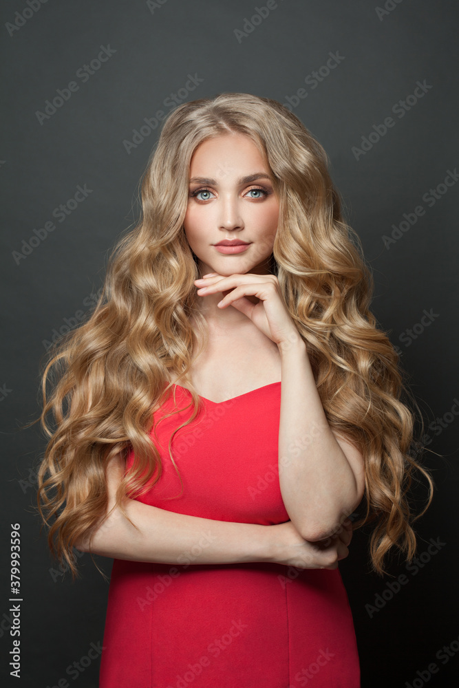 Beautiful blonde woman with healthy curly hairstyle wearing red dress portrait Beautiful blonde woman with healthy curly hairstyle wearing red dress portrait