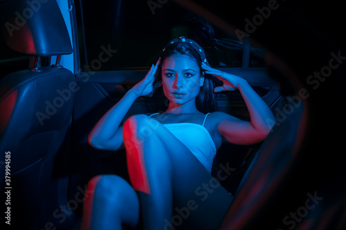 chica joven de moda en un coche con luces de colores moderno
