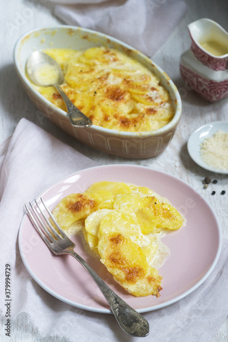 French dish Gratin Dauphinois in ceramic form on a light background. Rustic style.