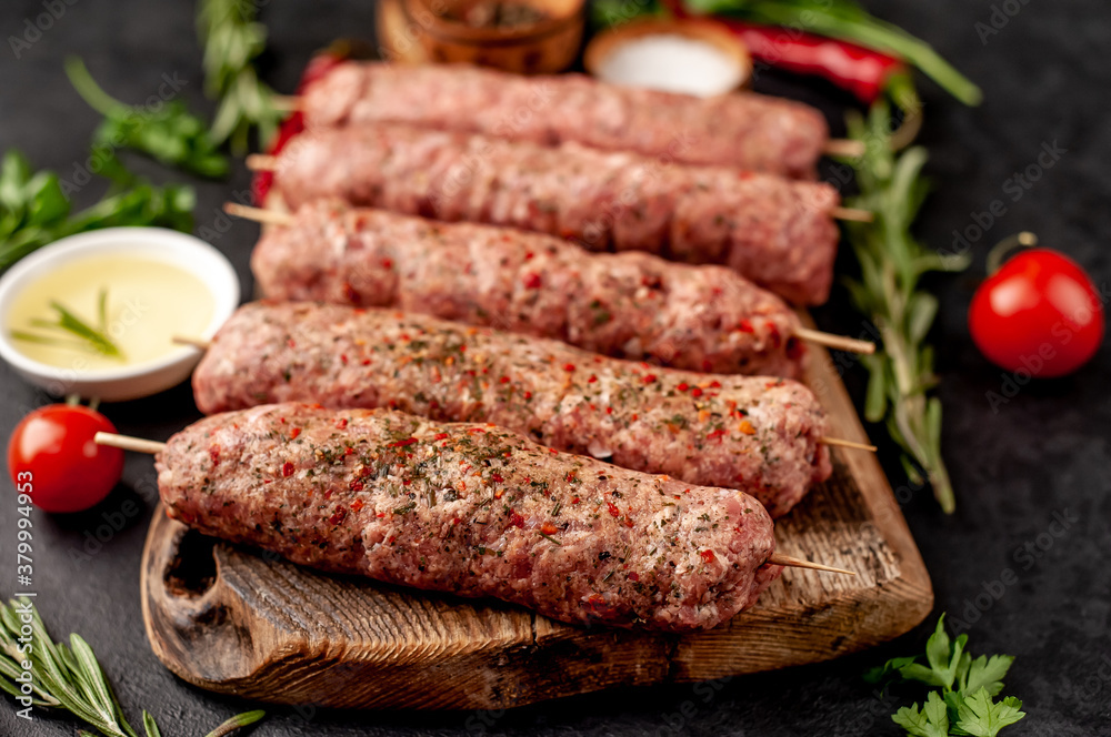 raw Lula kebab  on skewers with spices on a stone background 