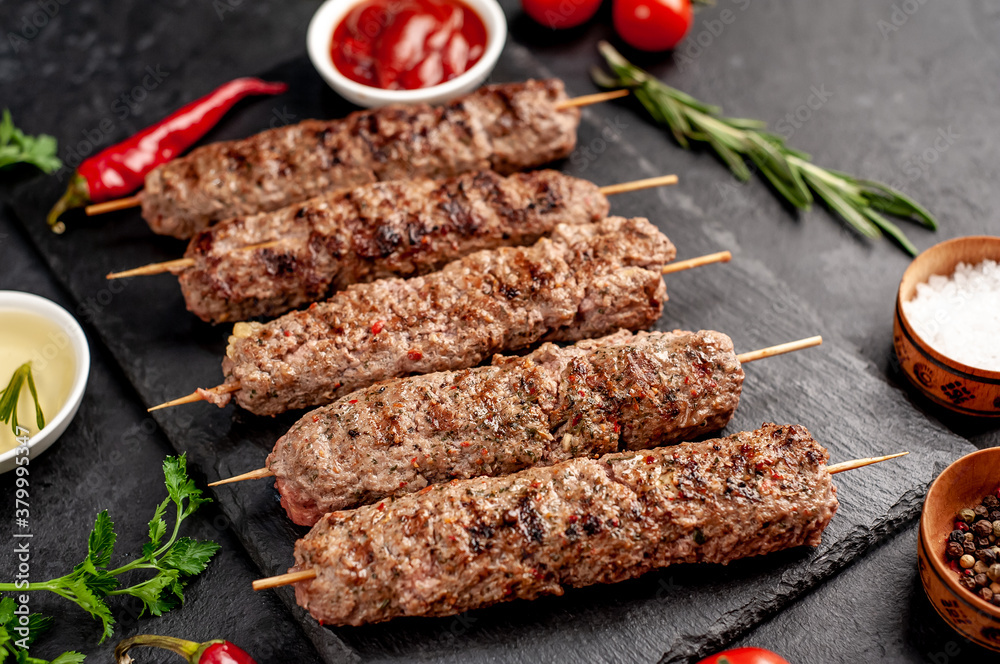 grilled Lula kebab on skewers with spices on a stone background

