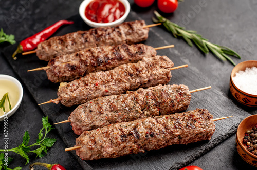 grilled Lula kebab on skewers with spices on a stone background

