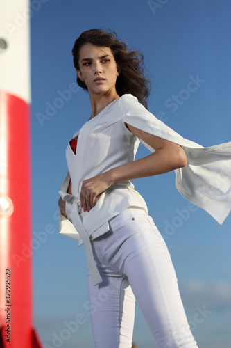 Girl in fluttering white clothes on the background of the lighthouse