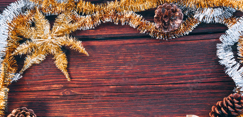 Yellow, orange, gold and silver shiny tinsel on a wooden background. Lots of empty space for lettering and design, Christmas card with pine cones. Beautiful horizontal Christmas background.