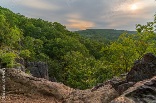 Beautiful sunset mountain landscape with sky, rocks and trees.