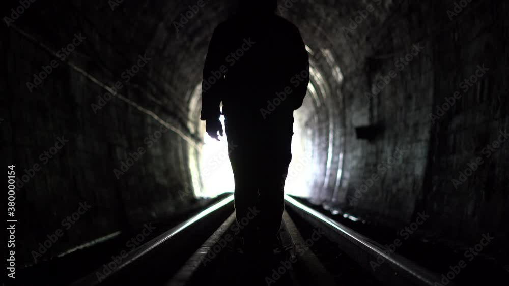 A person walking in a train tunnel A person walking in a train tunnel