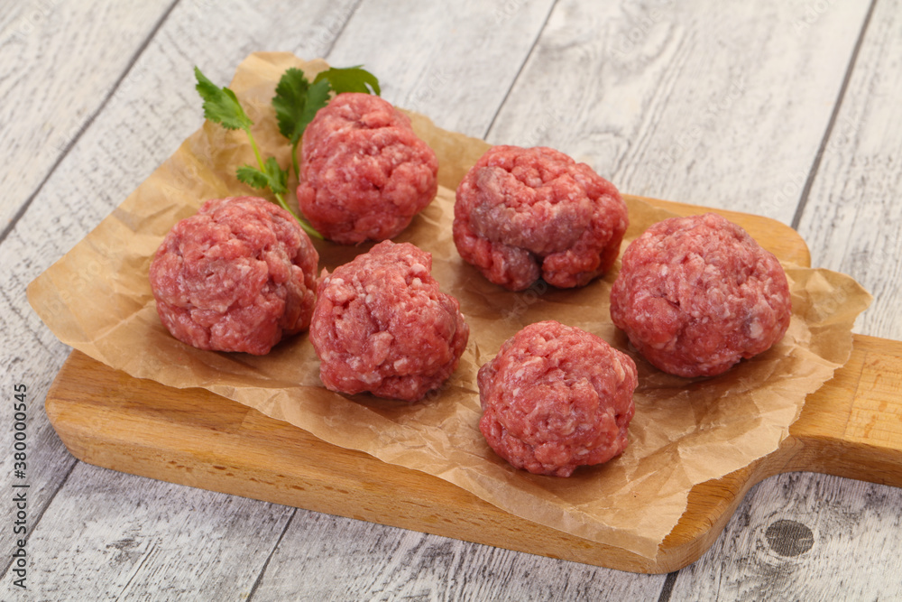 Raw meatball over wooden background Raw meatball over wooden background