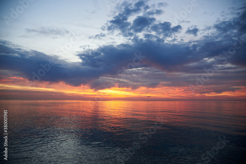 Beautiful cloudy sky at dawn, calm sea water. © Pavlo