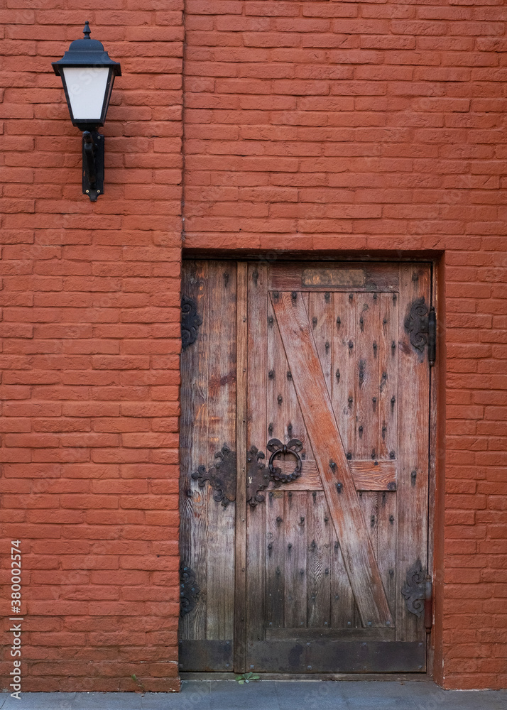Antique wooden door with metal hinges on a red brick wall. Antique wooden door with metal hinges on a red brick wall.