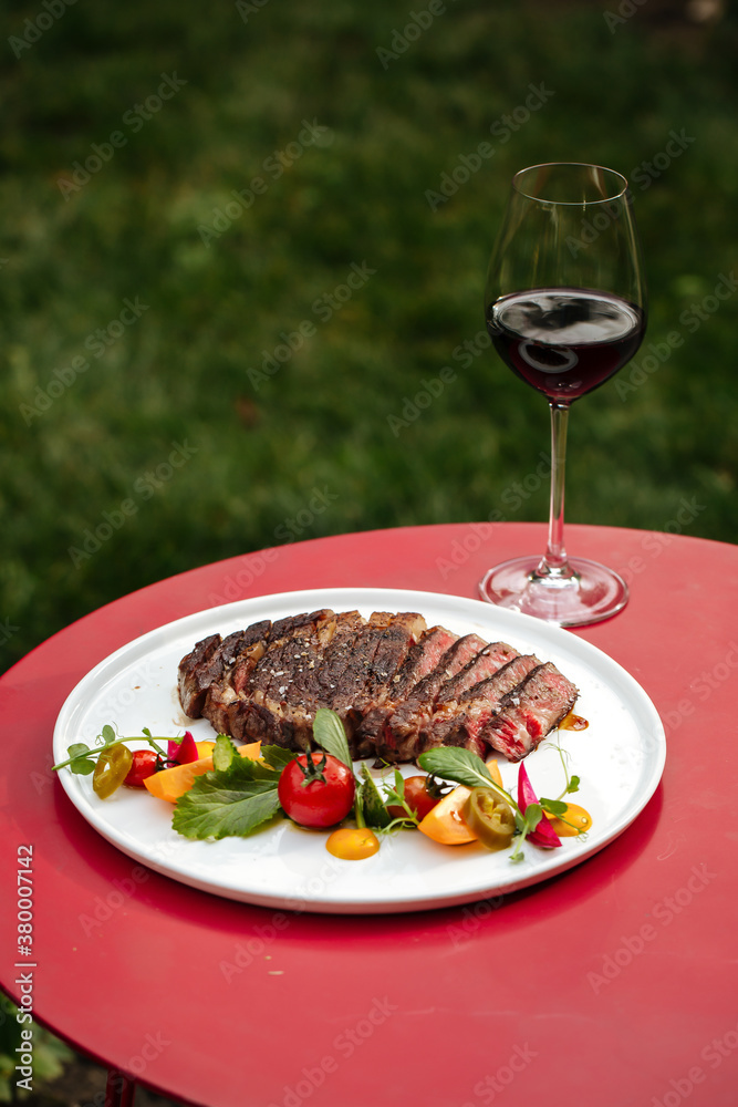 Ribeye beef steak with vegetable salad and wine