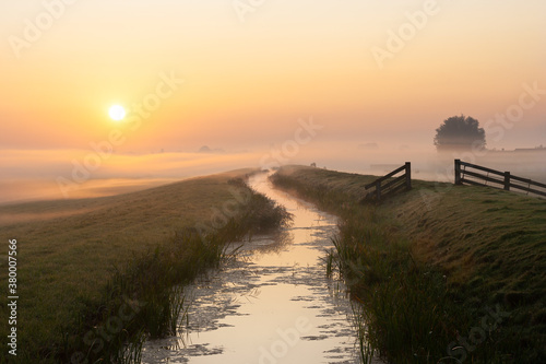 Scenic landscape image with the sun rising above a layer of fog in the dutch polder landscape