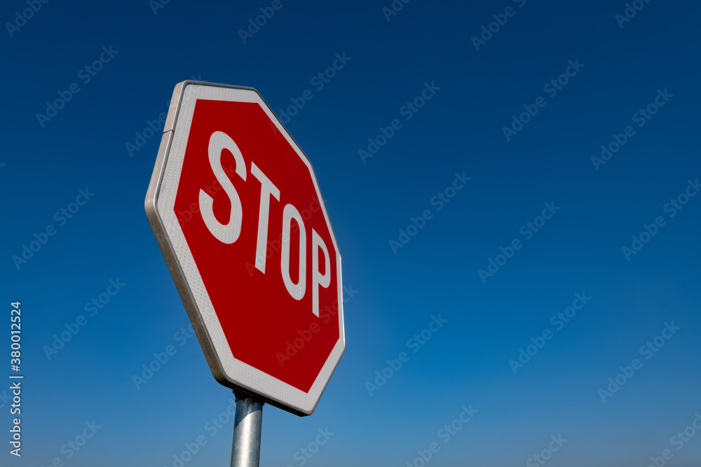 Stop Schild Verkehrsschild Halt Straße anhalten blauer Himmel rot weiß reflektierend Folie Buchstaben Straßenverkehrsordnung Deutschland international Symbol Achteck Oktagon achteckig Tafel Mast Sonne