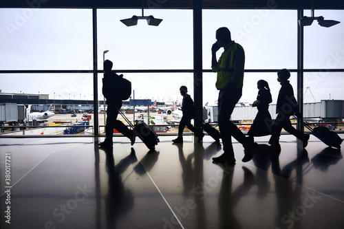 Silhouettes of air travelers navigating the terminal to board airplane flights amid pandemic.