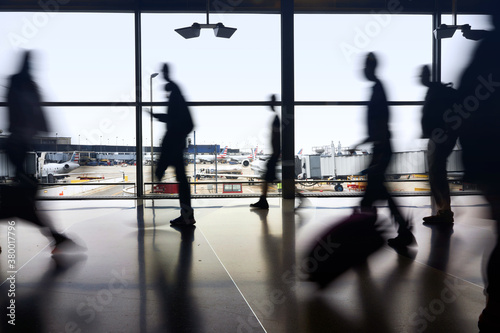 Silhouettes of air travelers navigating the terminal to board airplane flights amid pandemic.