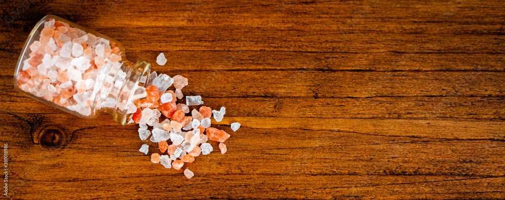 Close up pink and white natural Himalayan crystal rock mountain organic sea salt powder flake cook ingredient in grinder bottle glass on vintage rustic black kitchen wooden table Close up pink and white natural Himalayan crystal rock mountain organic sea salt powder flake cook ingredient in grinder bottle glass on vintage rustic black kitchen wooden table