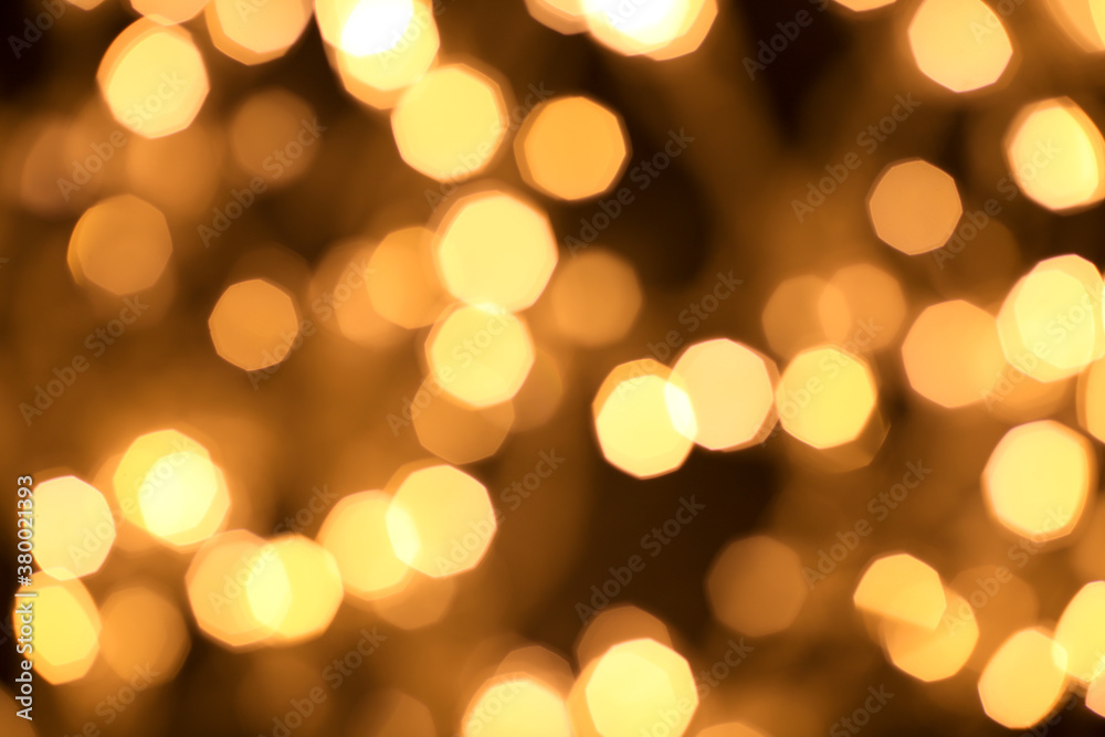 Christmas and Happy New Year on blurred bokeh of gold color on black background, glowing sparks, holiday lights, place for text Christmas and Happy New Year on blurred bokeh of gold color on black background, glowing sparks, holiday lights, place for text