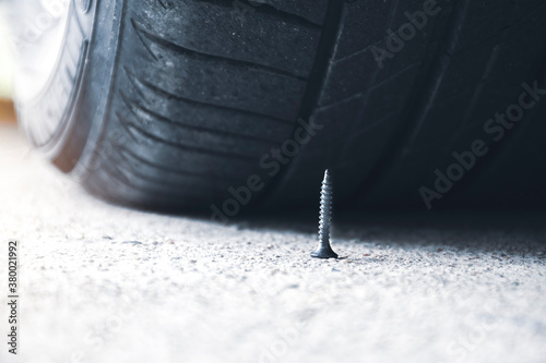 Close up of sharp metal screw on road nearly to puncture a car tire