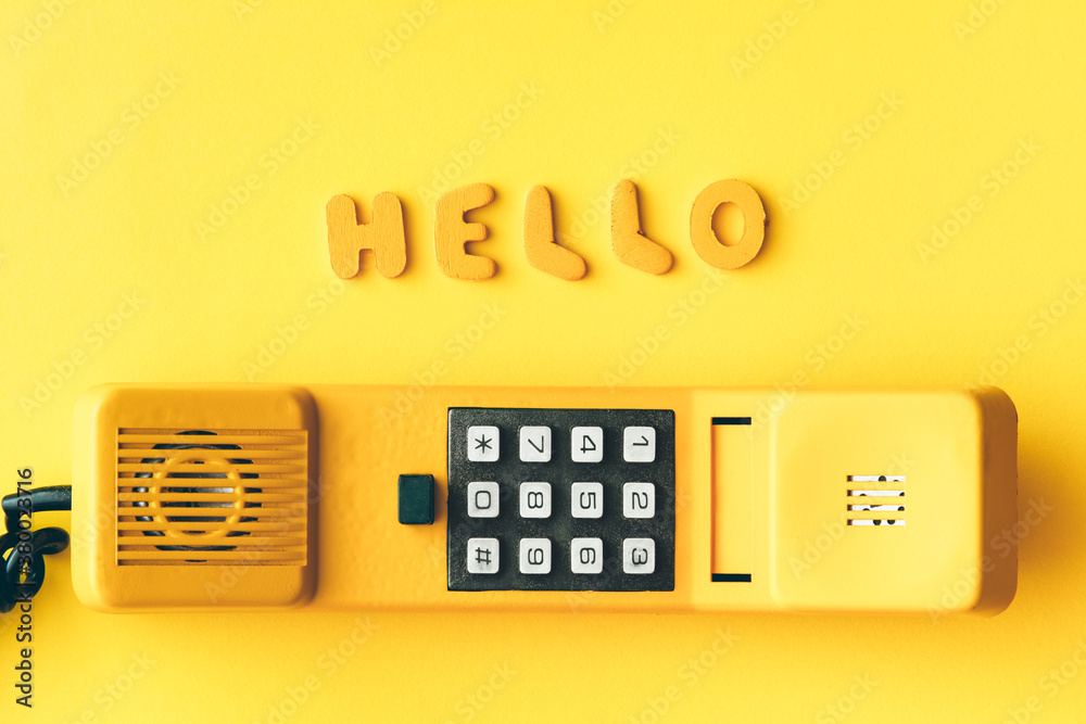 Friendly hello over old yellow phone handle Friendly hello over old yellow phone handle