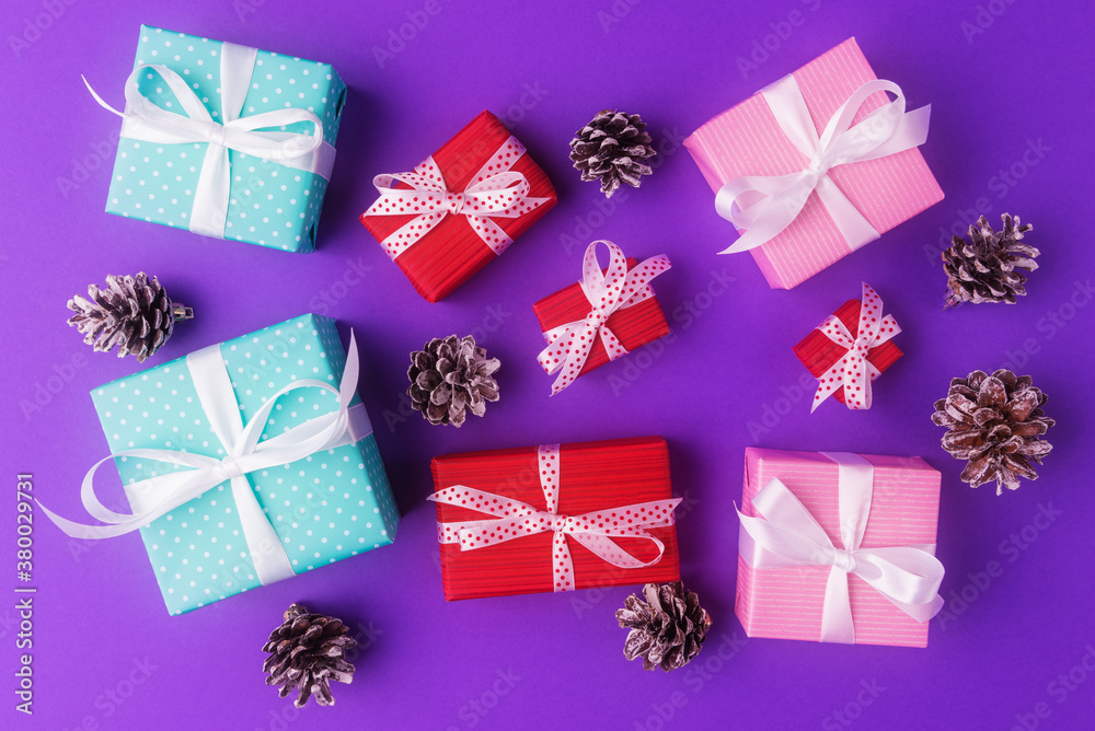 Gift boxes and fir cones on violet background. New Year and Christmas holiday concept Gift boxes and fir cones on violet background. New Year and Christmas holiday concept