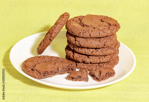 Chocolate oatmeal cookies on a white plate with a yellow background homemade baking concept