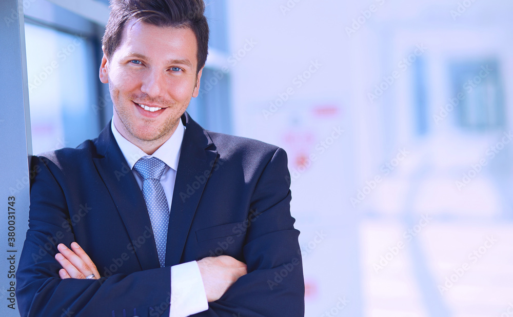 Portrait of businessman standing near window in office Portrait of businessman standing near window in office