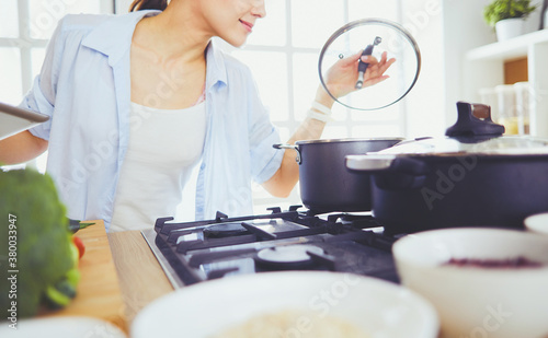 Young woman standing by the stove in the kitchen