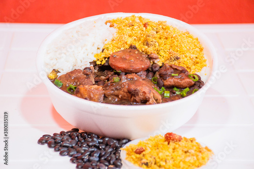 Feijoada. Typical Brazilian food with black beans, pork meat and sausage, deliver food, marmita ou marmitex with rice, beans, bean stew, collard Greens salad with orange e farofa. photo