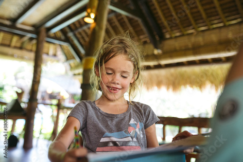 Little caucasian girl doing homework while on vacation photo