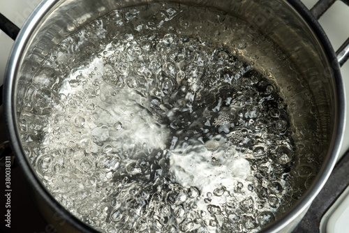 Water boils in a stainless steel pot. Boiling water surface.