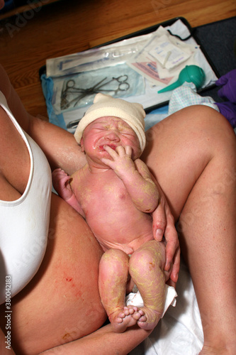 Mother cradles her newborn baby after a successful home birth photo