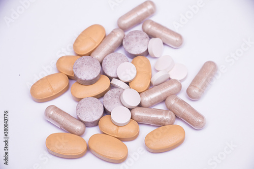 Mix of pills capsules supplements on white background photo