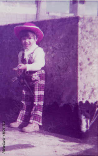 Scanned photo of a little boy playing cowboys with toy guns photo