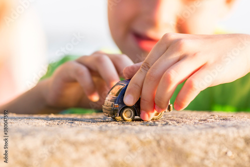Little boy play with a toy car summer outdoor. Little kid plays outdoor with toy car
