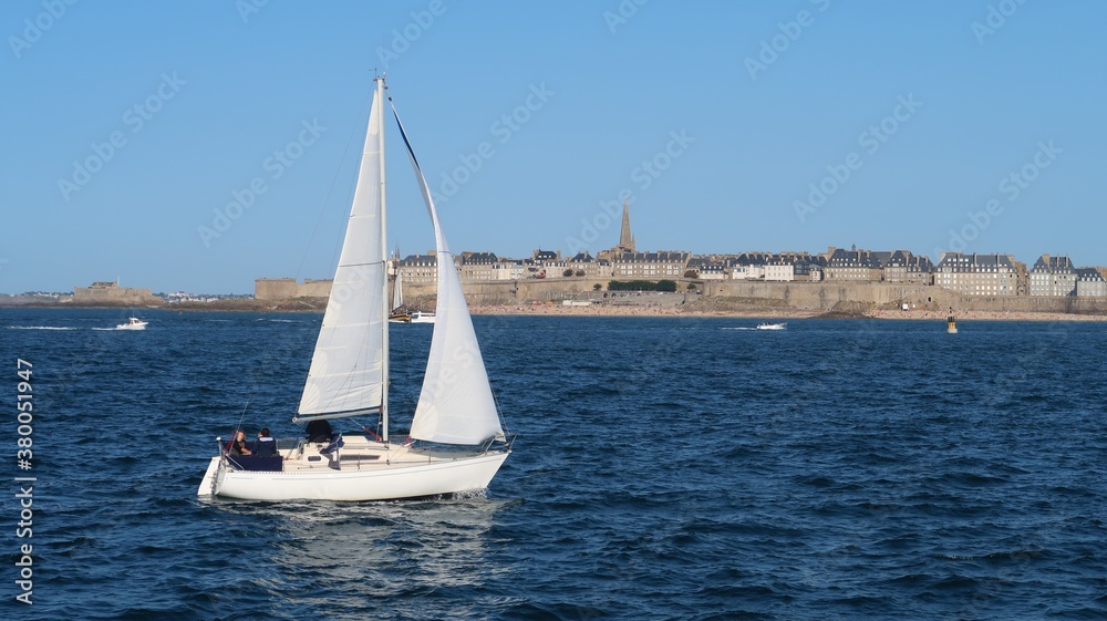 Nautisme dans la baie de Saint-Malo en Bretagne, navigation d'un voilier blanc sur la mer, sous un ciel bleu (France)