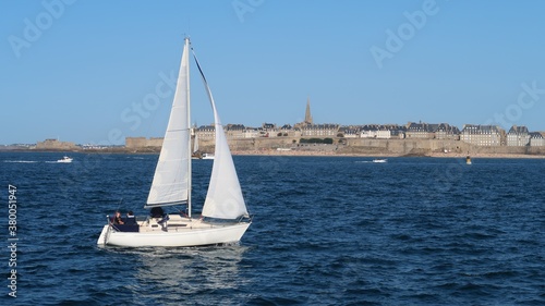 Nautisme dans la baie de Saint-Malo en Bretagne, navigation d'un voilier blanc sur la mer, sous un ciel bleu (France)