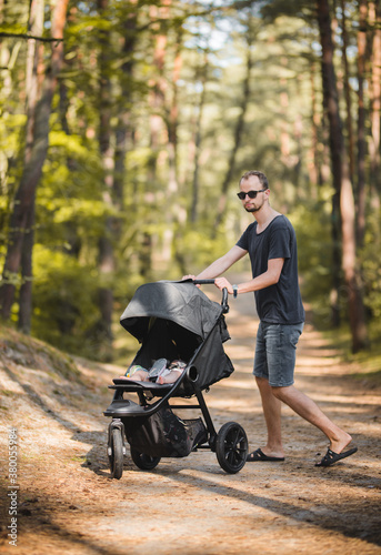 a father walking with a three wheel baby stroller photo