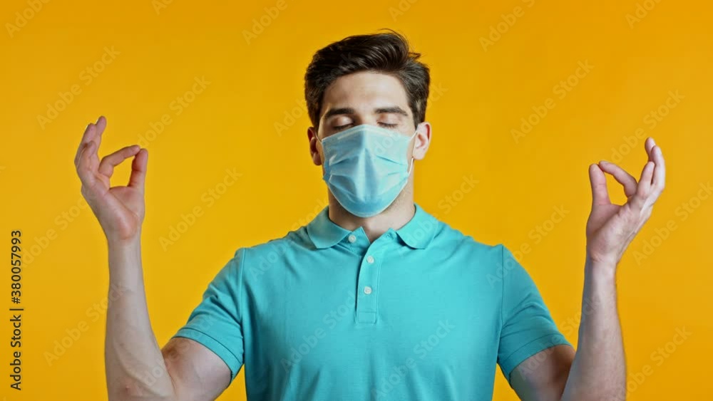 Pleased man in protective mask removed protective mask and throws it on floor as symbol of pandemic, epidemic end. Yellow studio background. Pleased man in protective mask removed protective mask and throws it on floor as symbol of pandemic, epidemic end. Yellow studio background.