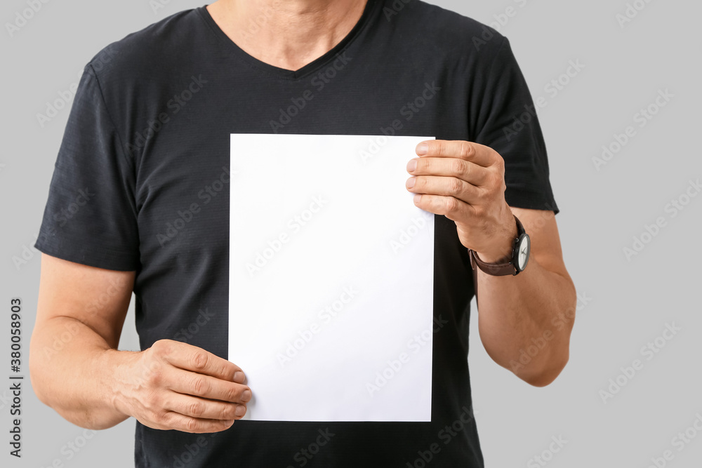 Man with blank paper sheet on grey background Man with blank paper sheet on grey background