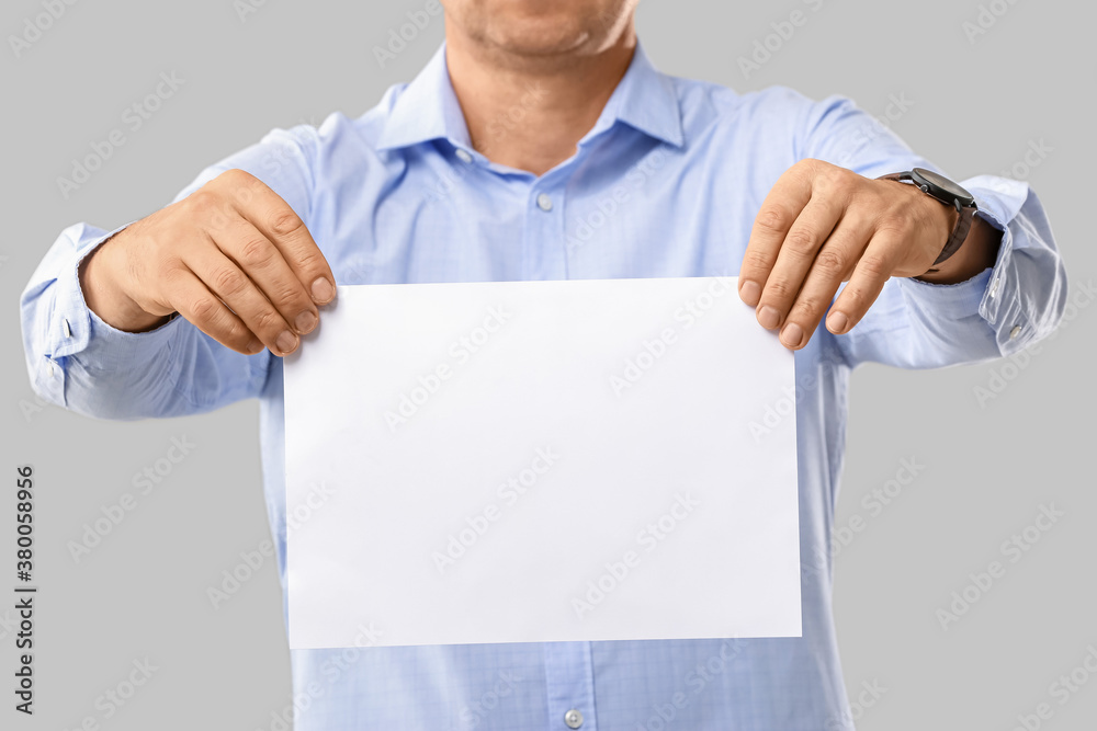 Man with blank paper sheet on grey background Man with blank paper sheet on grey background