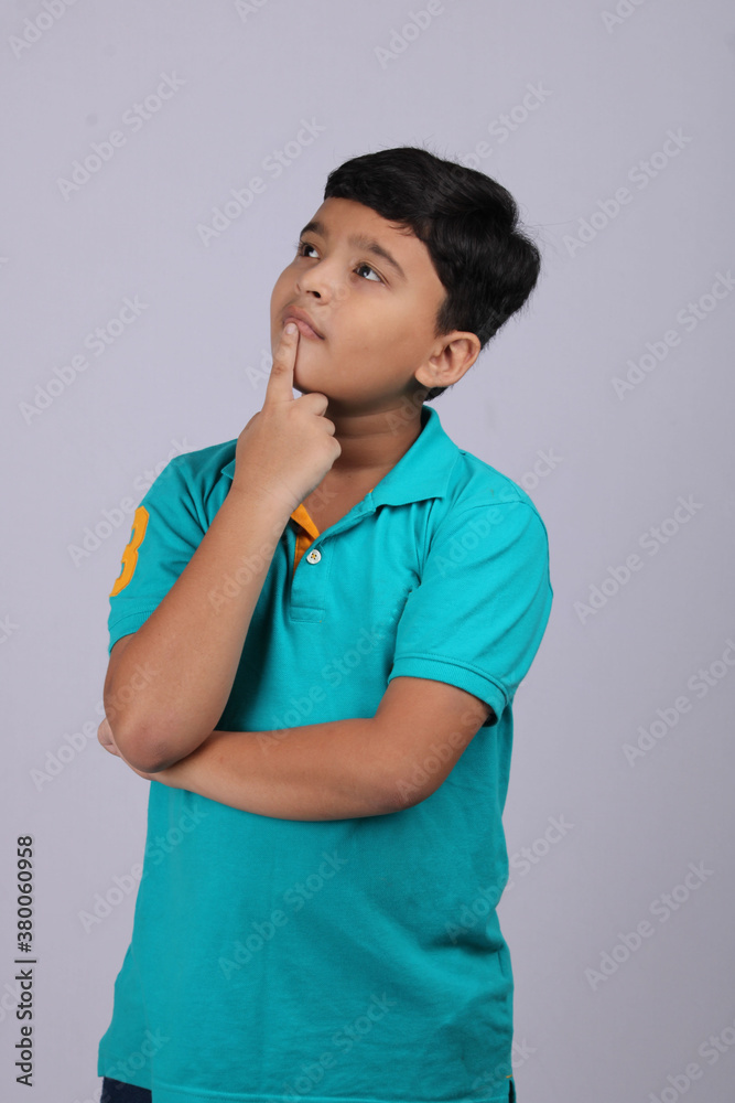 Thinking indian child deep in thought concept for confusion, brainstorming, indecision, uncertainty and choice Thinking indian child deep in thought concept for confusion, brainstorming, indecision, uncertainty and choice