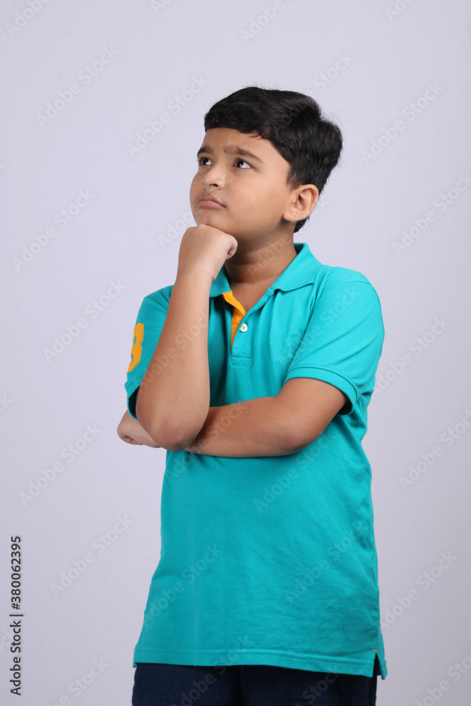 Thinking indian child deep in thought concept for confusion, brainstorming, indecision, uncertainty and choice Thinking indian child deep in thought concept for confusion, brainstorming, indecision, uncertainty and choice