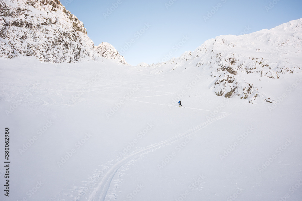 Man ski touring across mountain snow couloir