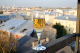 A glass of champagne on the background of city houses during sunset.