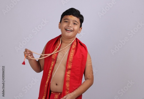 Indian boy in ethnic wear showing off his rosary or string of prayer beads with smile. photo